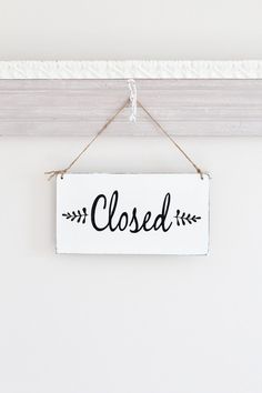 a closed sign hanging from the side of a white wall next to a wooden frame