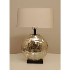 a glass table lamp with a white shade on the base and a black metal base