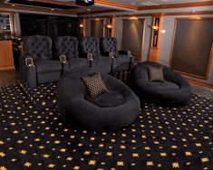 a large room with black chairs and gold stars on the carpet, in front of an entertainment center