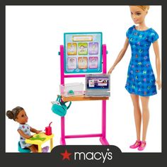 the doll is playing with her mother's play kitchen and toy easel set