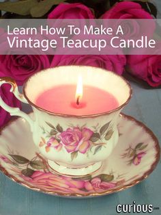 a teacup with a lit candle in it next to pink roses