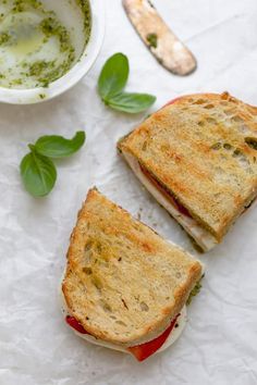 two grilled sandwiches with pesto on them next to a bowl of olive oil