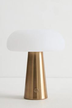 a gold table lamp with a white light on top