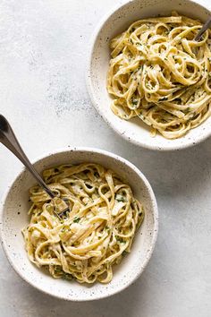 two bowls filled with pasta on top of a table