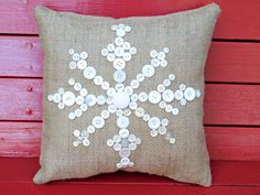 a pillow with buttons on it sitting on a red wooden bench in front of a wall