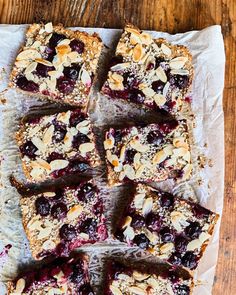 blueberry crumbled bars cut into squares on top of parchment paper and placed on a wooden table