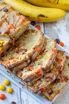 sliced loaf of fruitcake bread on a plate next to two bananas and candy candies