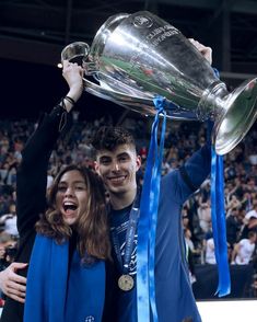 two people holding up a trophy in front of a crowd