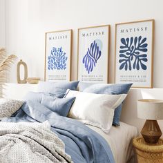 a bed with blue and white sheets in a bedroom next to two pictures on the wall