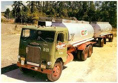 an old tanker truck is parked on the side of the road with trees in the background