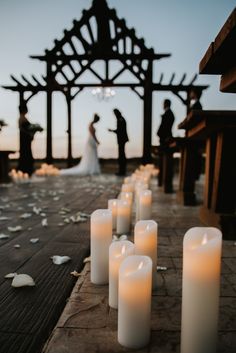 Denton outdoor wedding venue during a sunset ceremony in November. White petals and candles decorate the aisle on a hillside garden ceremony site with wooden touches and a water backdrop. Candle Wedding Aisle, November Outdoor Wedding, Wedding Altar Candles, Outdoor Wedding Candles, Led Candles Wedding, Wedding Aisle Candles, Sunset Wedding Colors, Romantic Outdoor Wedding Ceremony, Sunset Wedding Ceremony