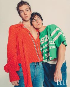 two young men standing next to each other with their arms around one another and looking at the camera