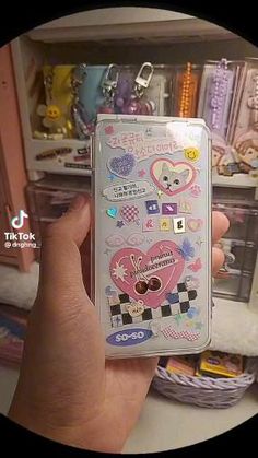 a person holding up a cell phone case with stickers on it's side