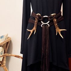 a black dress with deer antlers on it's belt is shown in front of a wicker chair