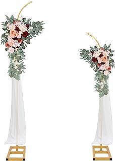 two tall vases with flowers and greenery on them, one is white and the other is pink