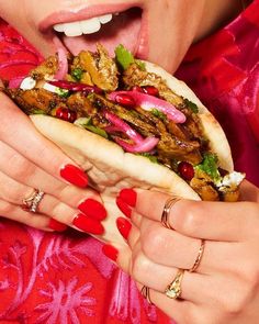 a woman with red nail polish holding a hot dog in her hands and tongue out