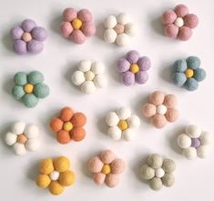 several different colored felt flowers on a white surface