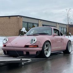 a pink porsche parked in front of a building