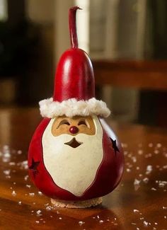 a red and white santa claus ornament sitting on top of a wooden table