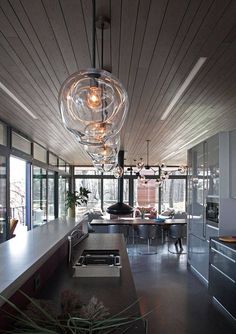 a modern kitchen with an island in the middle and lights hanging from it's ceiling