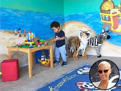 two children are playing with toys in a playroom that has a mural on the wall