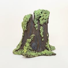 a fake tree stump with moss growing on it's sides and an opening in the trunk