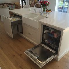 an open dishwasher sitting in the middle of a kitchen next to a sink