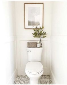 a white toilet sitting in a bathroom next to a framed picture on the wall above it