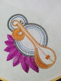 an embroidered design on a white cloth with purple and orange flowers in the center,