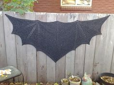 the bat is hanging on the fence next to some potted plants and other items