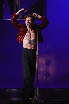 a shirtless man on stage with his hands in the air and holding a microphone