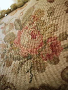 a close up view of a flowered pillow with tassels on the edge