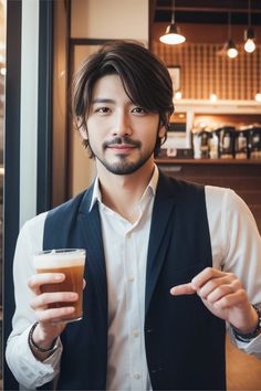 a man holding a drink and pointing to the side while wearing a vest in front of him