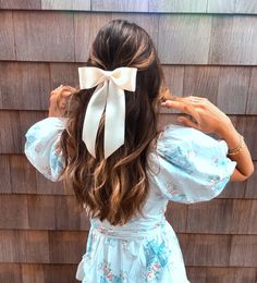 a woman with long hair wearing a blue dress and a white bow in her hair