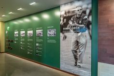 a hallway with green walls and pictures on the wall, along with posters about baseball players