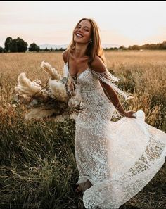 a beautiful woman in a white dress walking through a field with dried grass and flowers