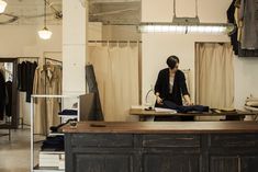 a woman sitting on top of a wooden counter in front of a closet filled with clothes