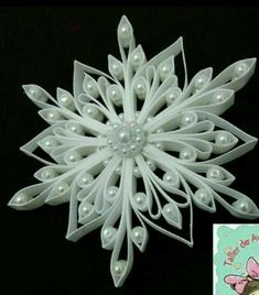 a snowflake made out of white plastic with pearls on the top and bottom