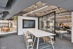 an office with tables, chairs and a flat screen tv in the middle of it