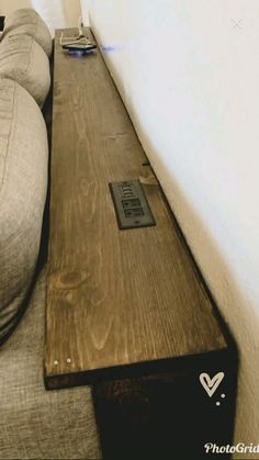 a couch sitting next to a wall with a wooden table on it's side