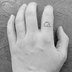 a person's hand with a small hedge tattoo on their left thumb and finger