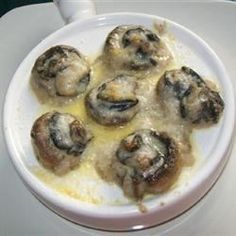 a white bowl filled with cooked mushrooms on top of a table