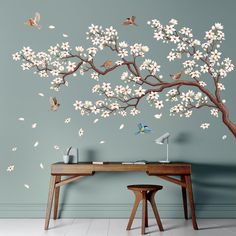 a tree with white flowers and birds on it is in front of a blue wall