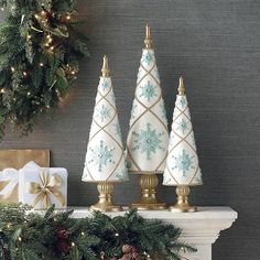 three small christmas trees on top of a mantle