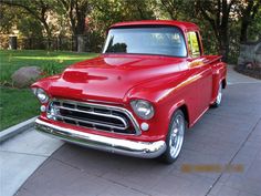 an old red truck is parked on the side of the road