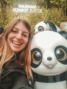 a woman is posing next to a panda statue