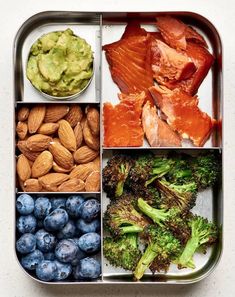 a metal tray filled with assorted food items including broccoli, blueberries and avocado