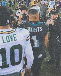 a group of football players standing on top of a field next to eachother