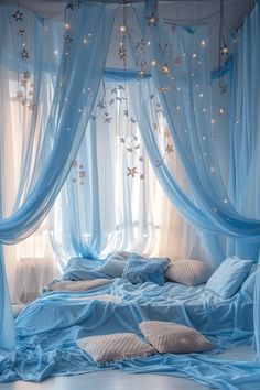 a bed covered in blue sheets and drapes with stars hanging from the ceiling above it