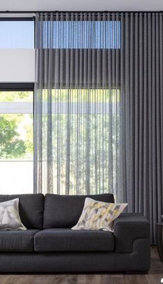 a living room filled with furniture and windows covered in grey drapes next to a plant